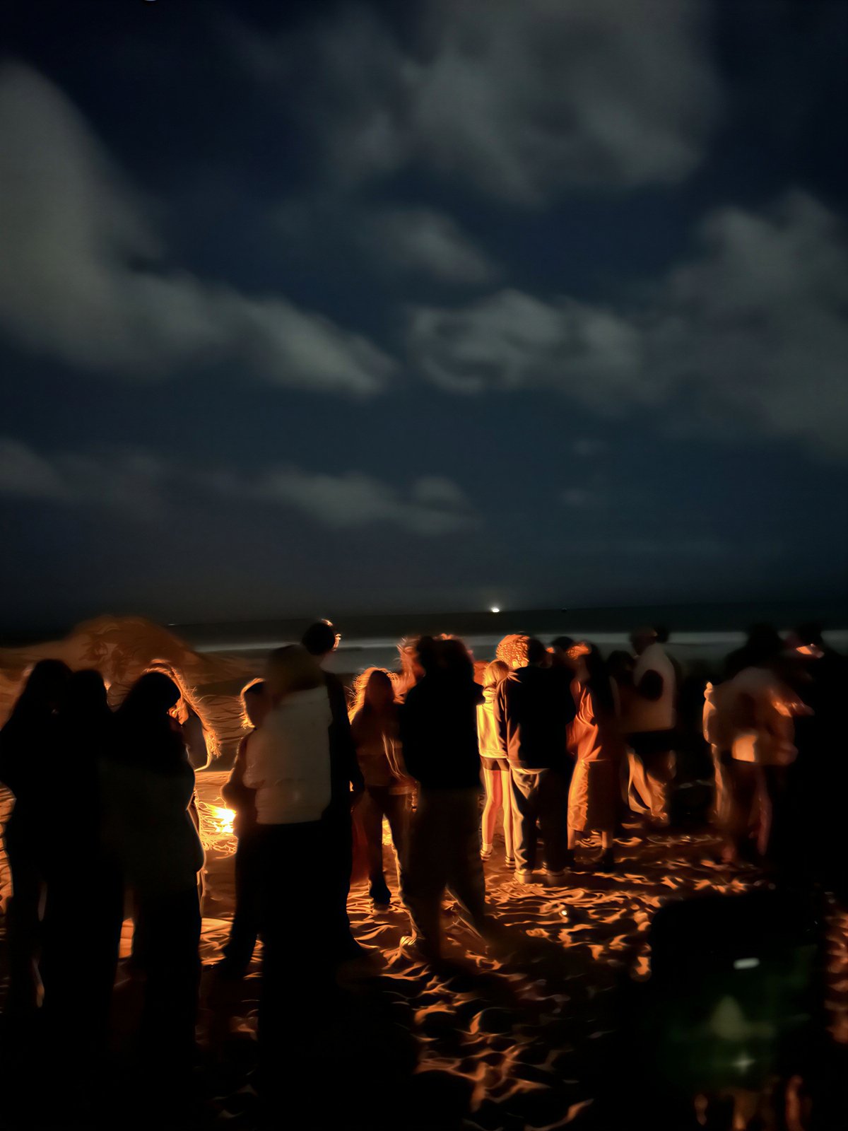 People gathered around a bonfire on the beach at night