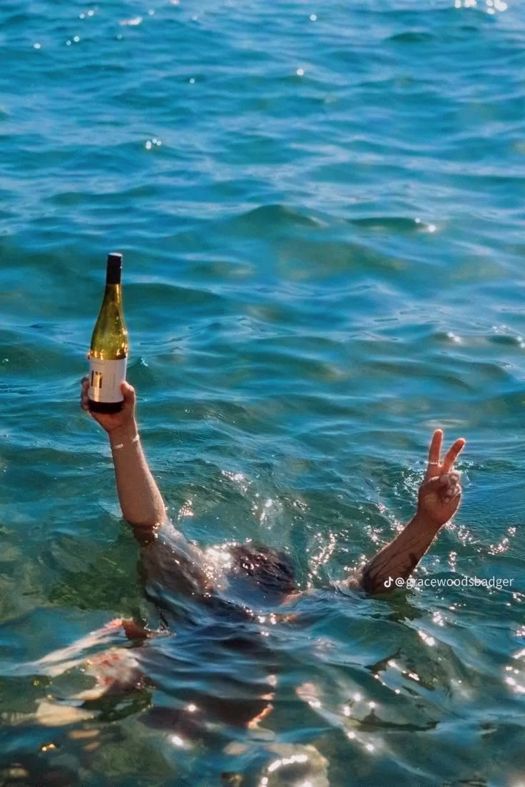 Person in the ocean celebrating with a bottle